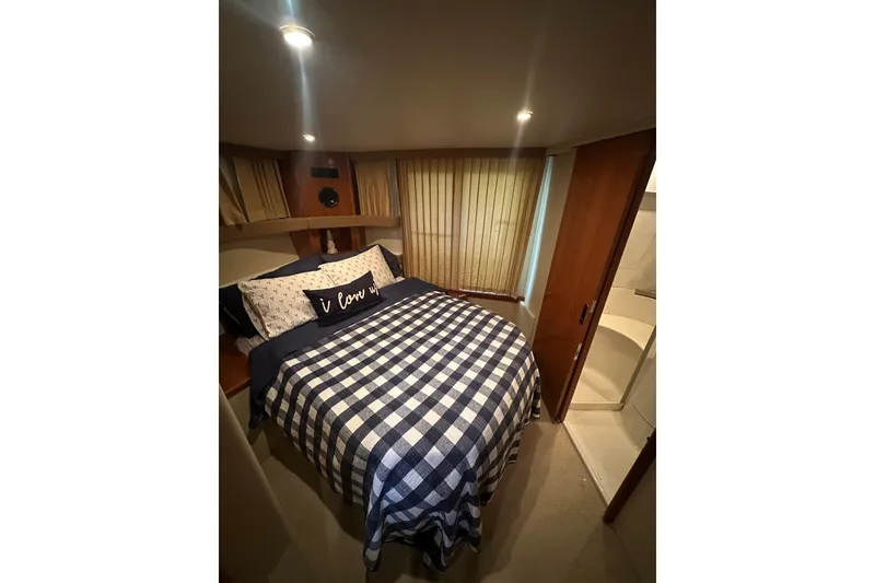 Slide: The Image of 2005 Carver 41 Cockpit Motor Yacht bedroom with checkered bedding and cozy lighting. - 9