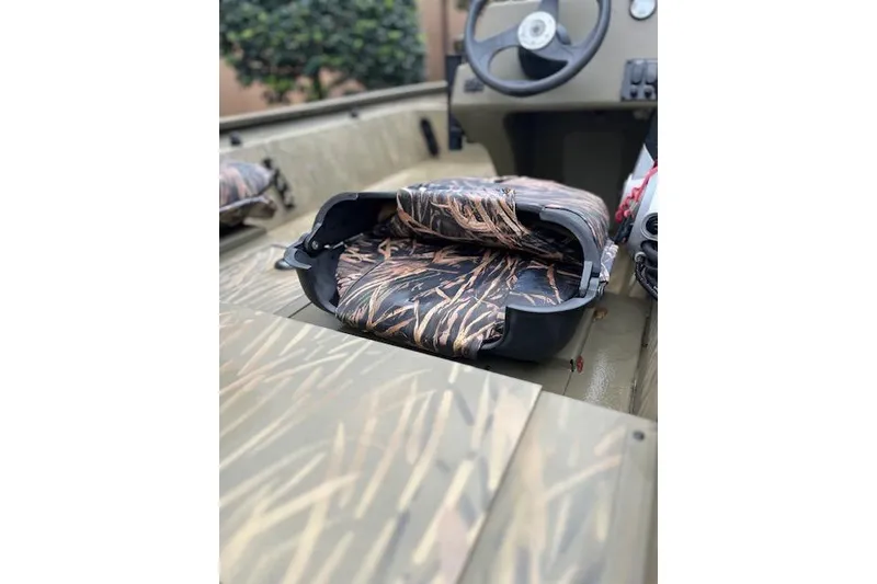 Slide: The Image of 2019 Tracker Grizzly 1754 MVX SC boat interior with camo seating and steering wheel. - 4