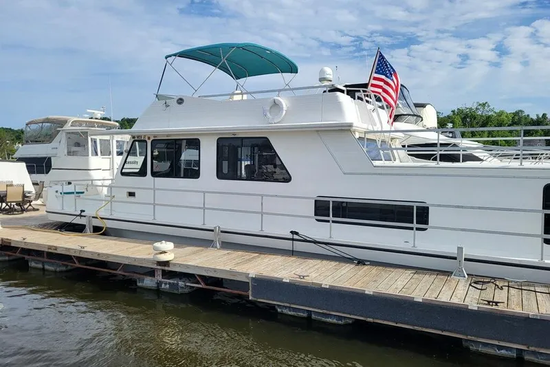 The Image of 1996 Gibson 50 Cabin Yacht docked, featuring American flag and blue canopy. - 0