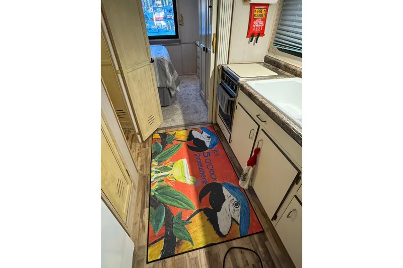 Slide: The Image of Interior of 1996 Gibson 50 Cabin Yacht with colorful parrot-themed rug in kitchen area. - 29