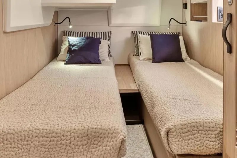Slide: The Image of 2026 Beneteau Swift Trawler 48 cabin with twin beds, cozy bedding, and reading lights. - 9