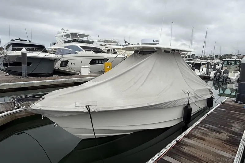 Slide: The Image of 2024 Boston Whaler 250 Outrage boat docked at a marina, surrounded by other vessels. - 12