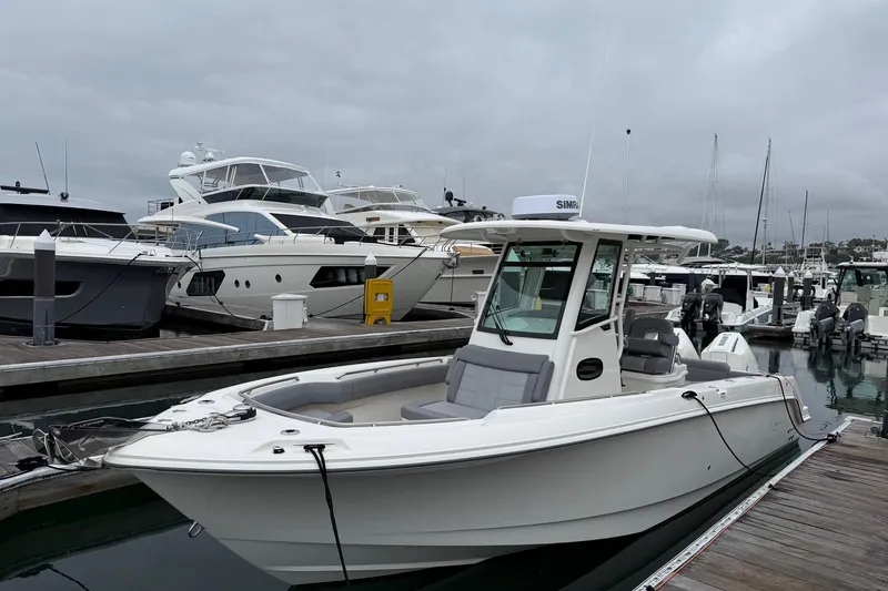 Slide: The Image of 2024 Boston Whaler 250 Outrage navigating a marina with waterfront homes and boats. - 3