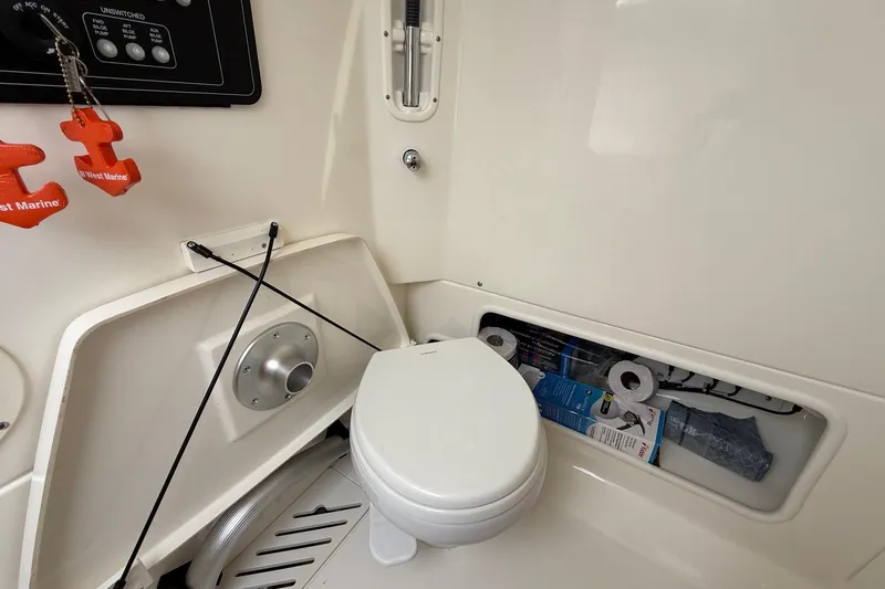 Slide: The Image of 2024 Boston Whaler 250 Outrage fishing rod storage compartment with organized gear and speaker. - 35