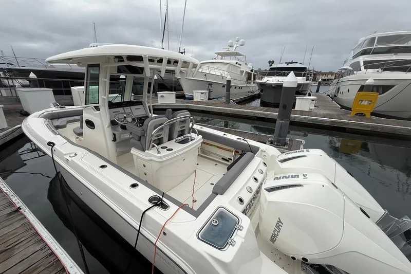 Slide: The Image of 2024 Boston Whaler 250 Outrage boat cruising in a marina with waterfront homes. - 4