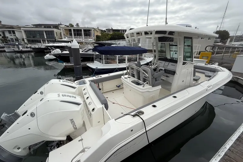 Slide: The Image of 2024 Boston Whaler 250 Outrage boat cruising in a marina with waterfront homes. - 5