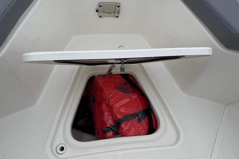Slide: The Image of Open storage compartment on 2024 Boston Whaler 250 Outrage boat with red life jacket inside. - 55