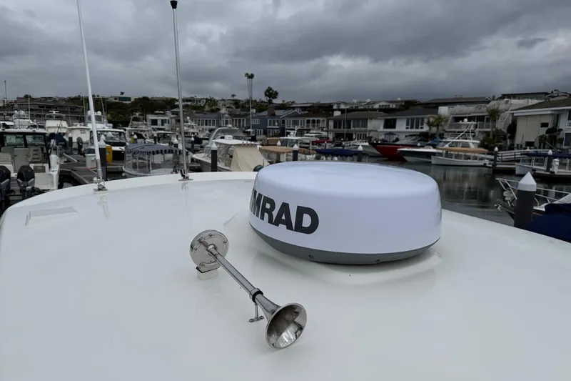 Slide: The Image of 2024 Boston Whaler 250 Outrage boat with radar, docked in a marina under cloudy skies. - 57