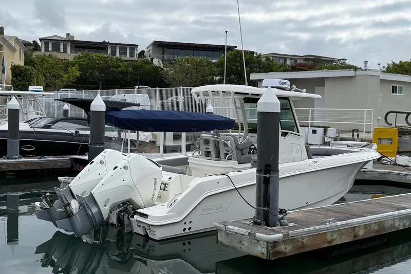 Slide: The Image of 2024 Boston Whaler 250 Outrage boat on calm water near residential docks. - 6