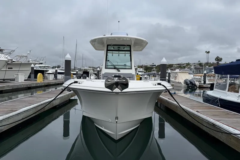 Slide: The Image of 2024 Boston Whaler 250 Outrage boat cruising in a marina with waterfront homes. - 8