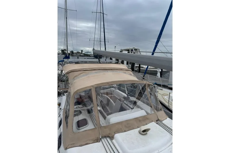 Slide: The Image of 2005 Hunter 38 sailboat with beige canopy docked at marina under cloudy skies. - 11