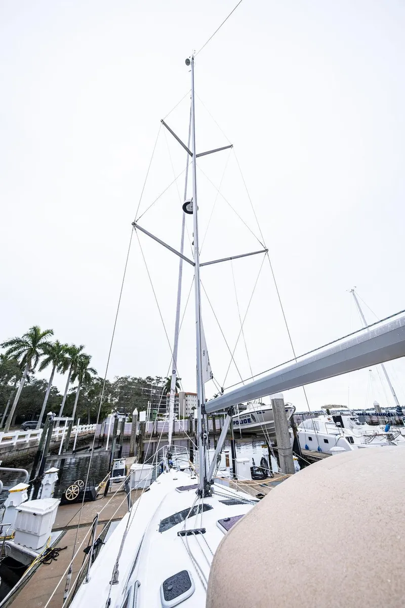 Slide: The Image of 2005 Hunter 38 sailboat docked, showcasing tall mast and marina setting. - 16