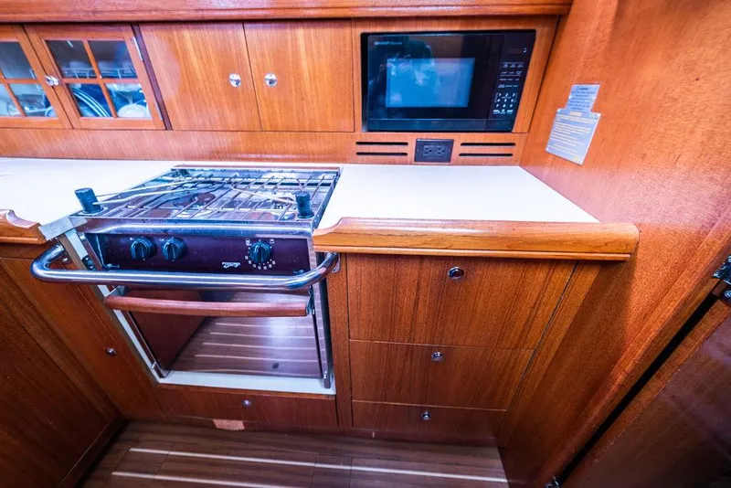 Slide: The Image of Wooden yacht kitchen with stove, microwave, and cabinets in a 2005 Hunter 38 model. - 46