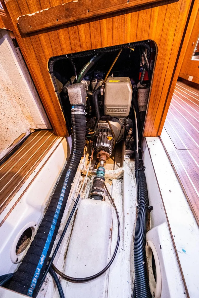 Slide: The Image of Engine compartment of a 2005 Hunter 38 sailboat, showcasing mechanical components and wooden paneling. - 72