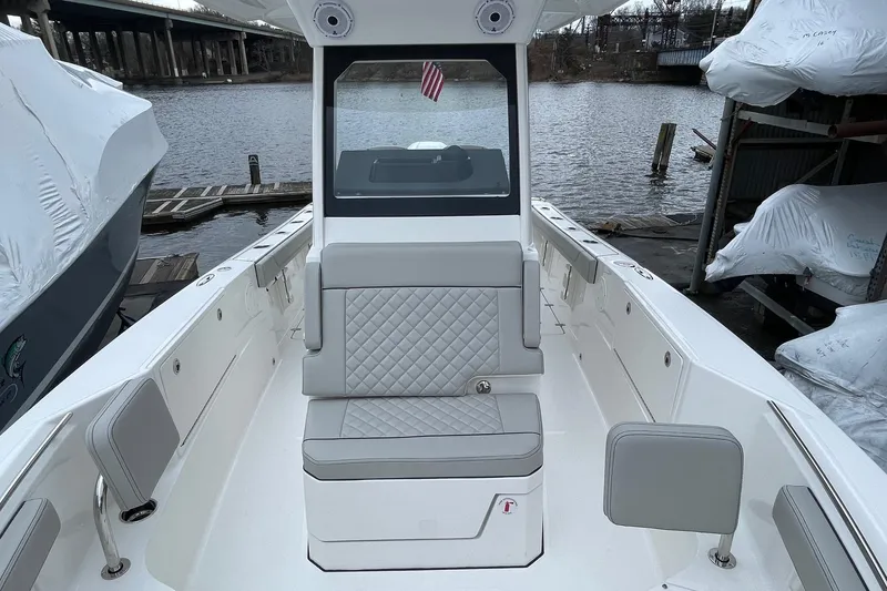 Slide: The Image of 2024 Pursuit S 248 Sport boat interior with gray seating, dockside view. - 17