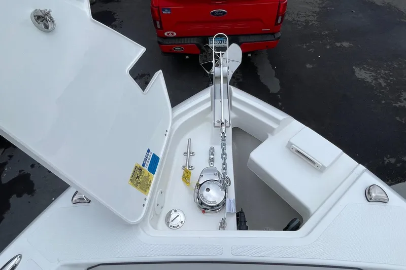 Slide: The Image of 2024 Pursuit S 248 Sport boat anchor compartment with open hatch, showcasing anchor chain and winch. - 20