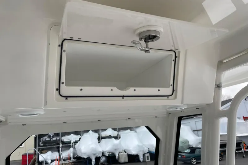 Slide: The Image of 2024 Pursuit S 248 Sport boat interior storage compartment with latch, showcasing sleek design. - 24