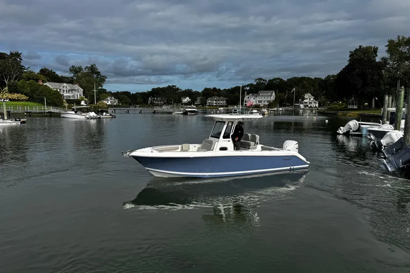 Slide: The Image of 2024 Pursuit S 248 Sport boat cruising in a scenic harbor with waterfront homes. - 3