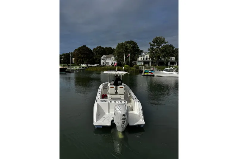 Slide: The Image of 2024 Pursuit S 248 Sport boat on calm water near waterfront homes. - 5