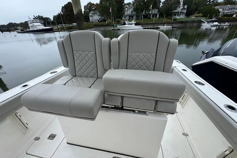 Slide: The Image of 2024 Pursuit S 248 Sport boat with luxurious gray seating, docked by a serene waterfront. - 9