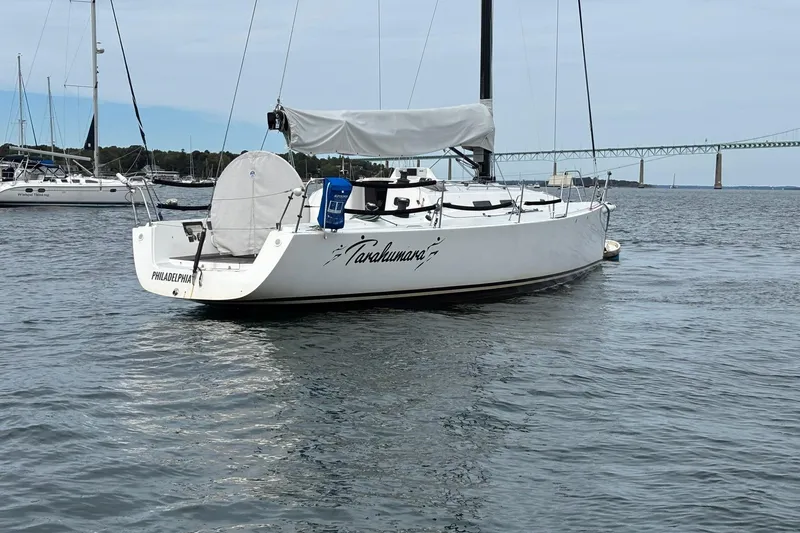 Slide: The Image of 2008 J Boats J/122 sailboat anchored in calm waters near a bridge. - 2
