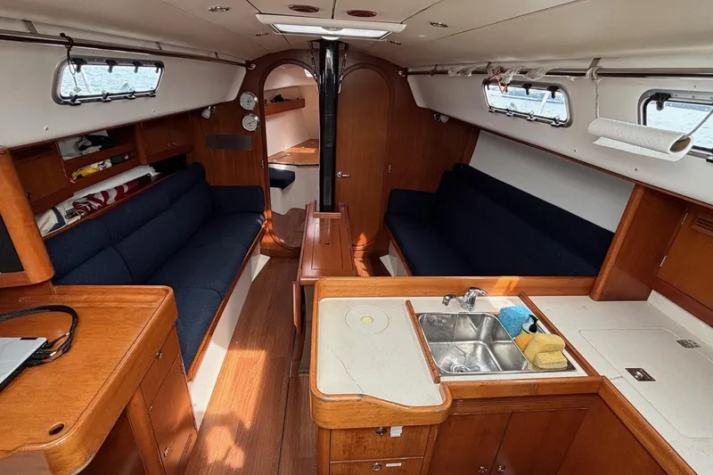 Slide: The Image of 2008 J Boats J/122 interior with wood finish, blue seating, and compact kitchen area. - 28