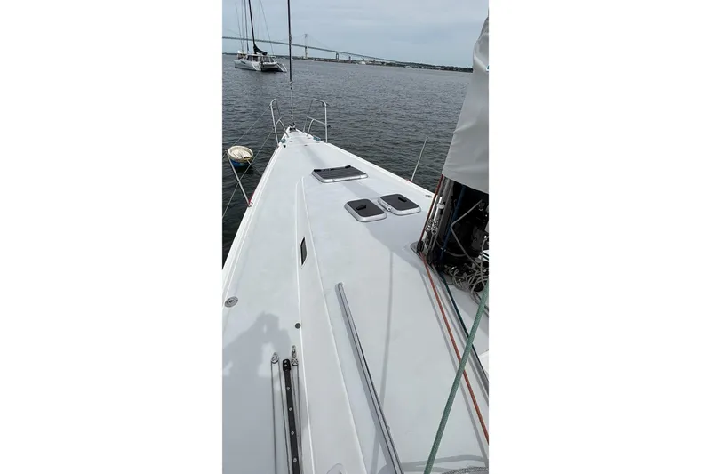 Slide: The Image of 2008 J Boats J/122 sailboat deck with ropes and hatches, moored near a bridge. - 7