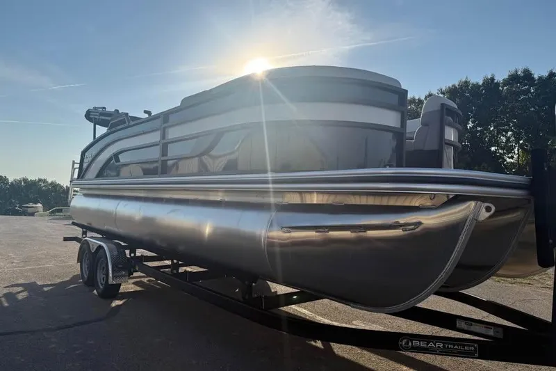 Slide: The Image of 2026 Lowe SS 230 DV pontoon boat on trailer, sunlit background. - 2