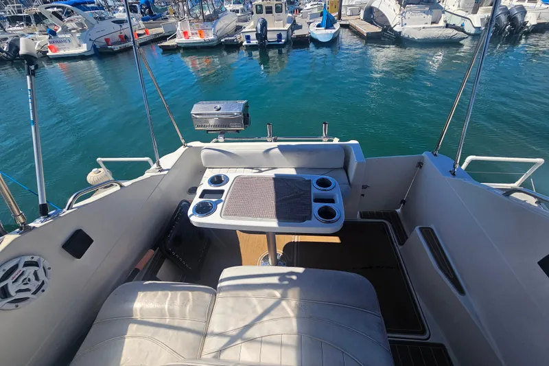 Slide: The Image of 1999 Maxum 2400 SCR boat interior with seating, table, and marina view. - 11