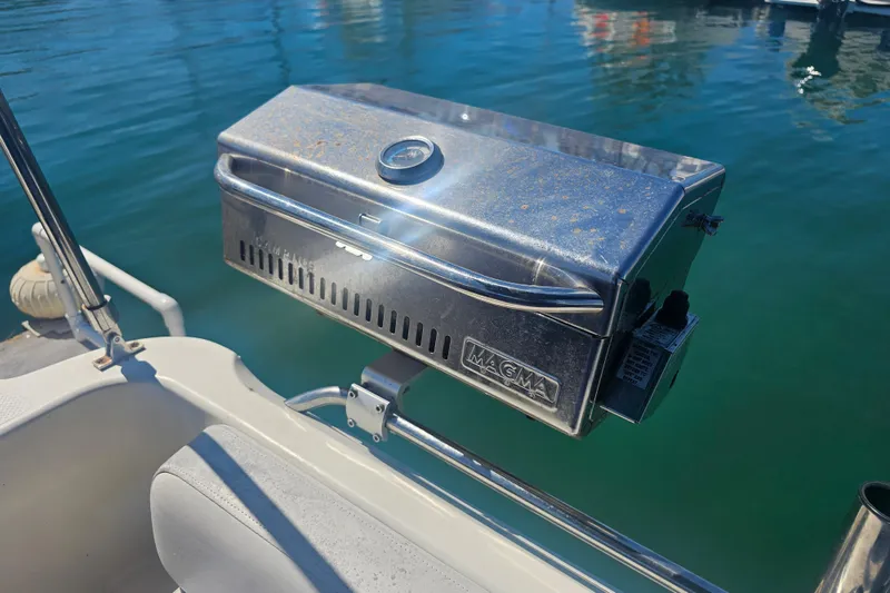 Slide: The Image of Stainless steel Magma grill on 1999 Maxum 2400 SCR boat, docked by clear water. - 12
