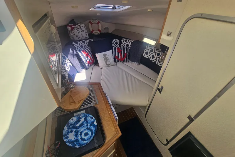 Slide: The Image of Interior of 1999 Maxum 2400 SCR boat with cozy seating and nautical decor. - 16