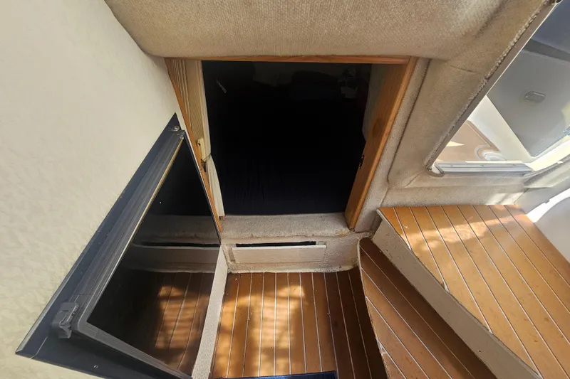 Slide: The Image of Interior view of 1999 Maxum 2400 SCR boat with wooden flooring and cabin entrance. - 18