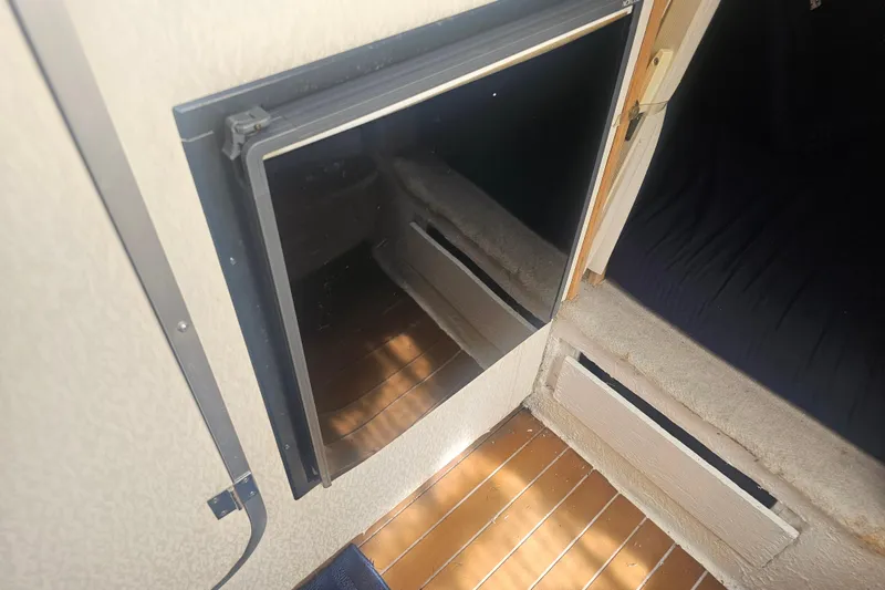 Slide: The Image of 1999 Maxum 2400 SCR cabin interior with open fridge and wooden flooring. - 19