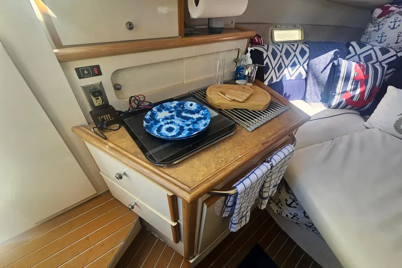 Slide: The Image of 1999 Maxum 2400 SCR cabin interior with kitchenette, nautical decor, and cozy seating area. - 20