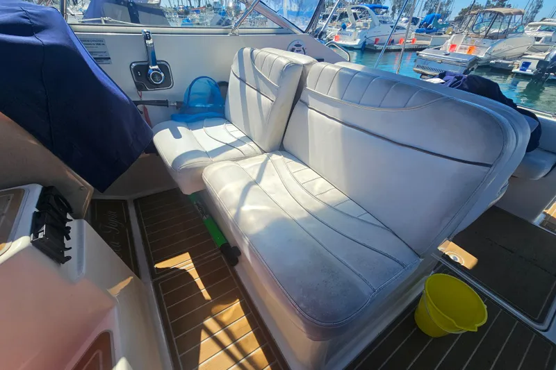 Slide: The Image of 1999 Maxum 2400 SCR boat interior with white seating and marina view. - 8
