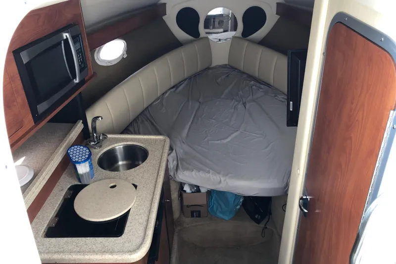 Slide: The Image of 2008 Rinker 260 Express Cruiser cabin with kitchenette and bed. - 11