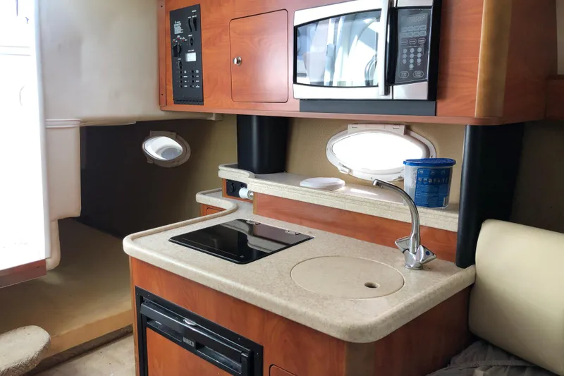 Slide: The Image of 2008 Rinker 260 Express Cruiser interior kitchen with sink, stove, and microwave. - 12