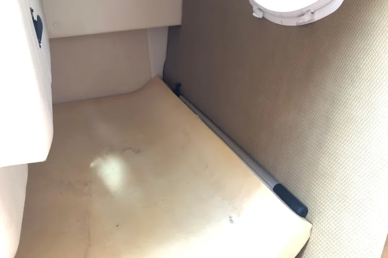 Slide: The Image of Interior cabin view of 2008 Rinker 260 Express Cruiser, featuring a beige cushion and wall. - 13