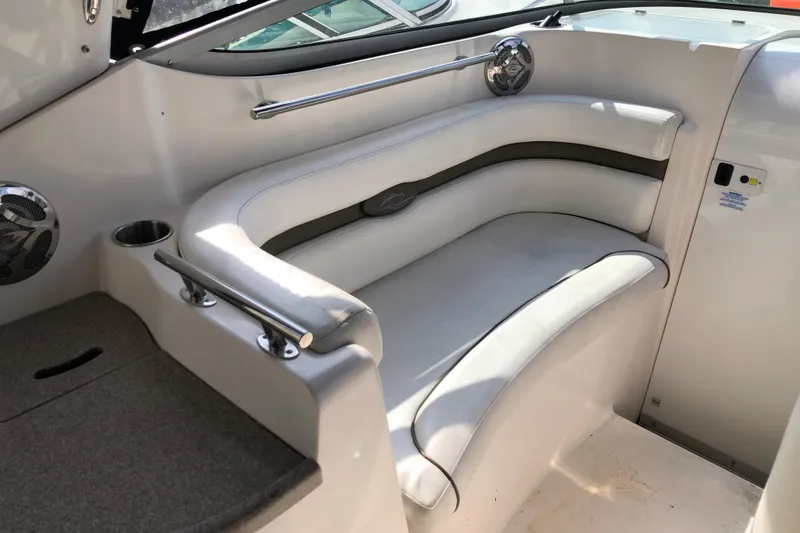 Slide: The Image of 2008 Rinker 260 Express Cruiser interior seating with white upholstery and stainless steel accents. - 6