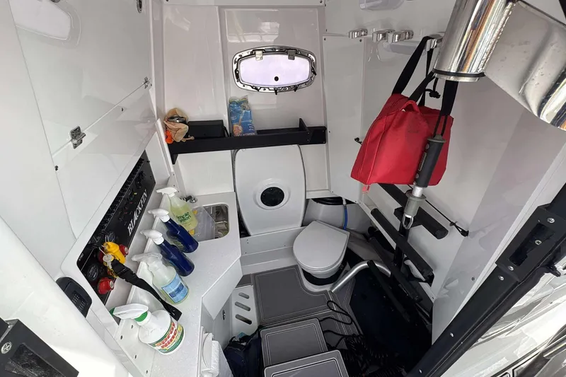 Slide: The Image of 2023 Blackfin 332cc boat interior with storage, cleaning supplies, and compact toilet. - 13