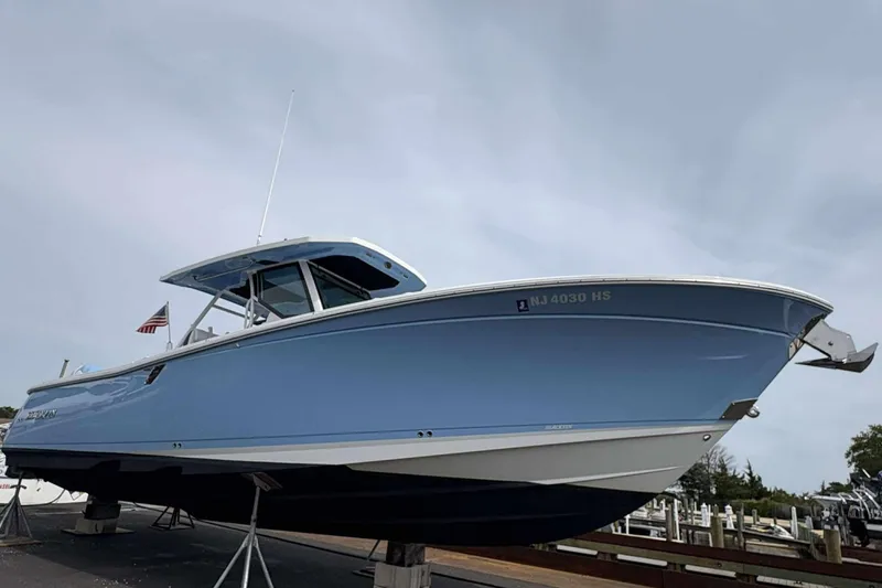 Slide: The Image of 2023 Blackfin 332cc boat in light blue, docked with American flag. - 2
