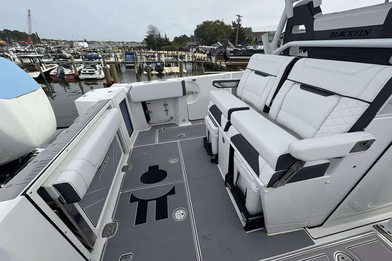 Slide: The Image of 2023 Blackfin 332cc boat interior with luxurious seating and sleek design at a marina. - 21