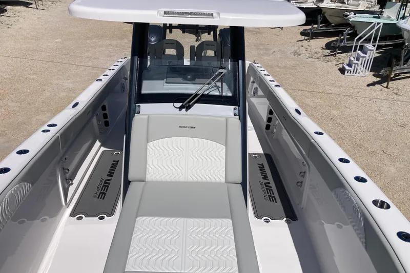 Slide: The Image of 2026 Twin Vee 280 GFX CC boat interior with seating and console, docked outdoors. - 11