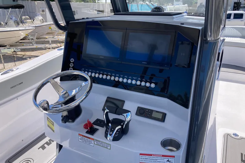 Slide: The Image of 2026 Twin Vee 280 GFX CC boat dashboard with steering wheel and electronic controls. - 8