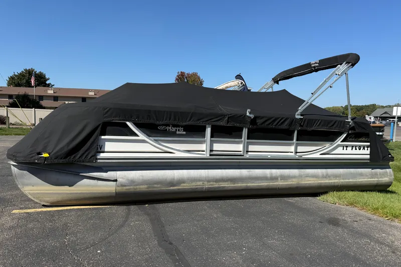Slide: The Image of 2005 Harris FloteBote 270 Crowne pontoon boat with black cover on pavement. - 1