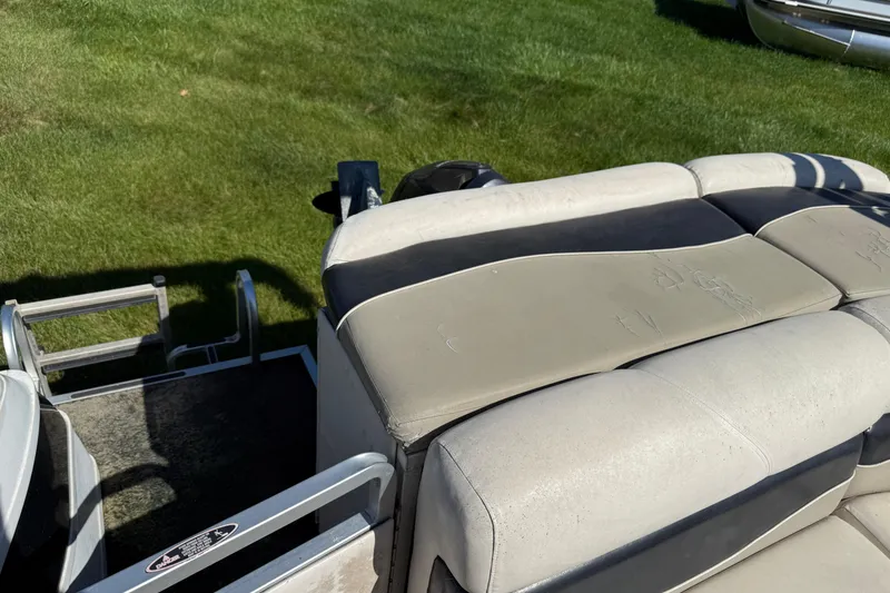 Slide: The Image of 2005 Harris FloteBote 270 Crowne boat with cushioned seating and ladder on grassy area. - 23