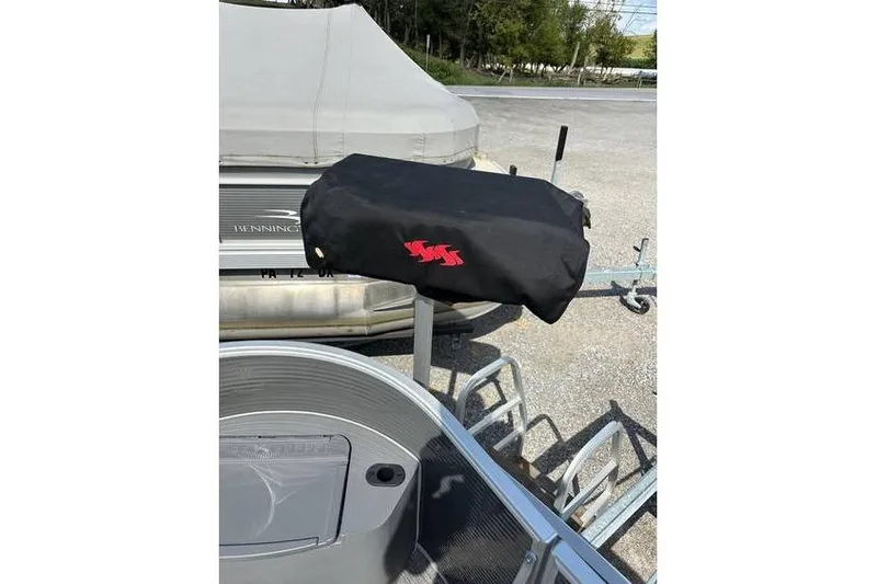 Slide: The Image of 2025 Bennington 20 SF Family boat with covered fishing seat, parked on a trailer. - 15