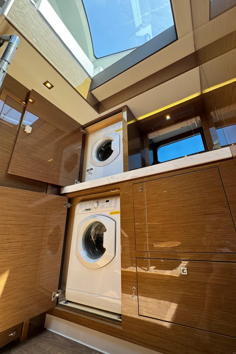 Slide: The Image of 2021 Cruisers Yachts 60 Cantius Flybridge laundry area with washer and dryer, skylight above. - 38