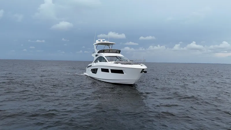 Slide: The Image of 2021 Cruisers Yachts 60 Cantius cruising on open water under cloudy skies. - 2
