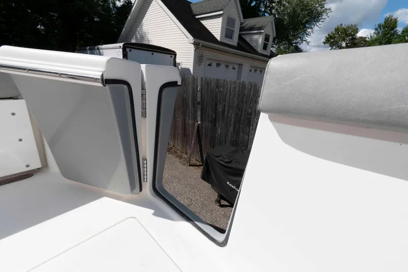 Slide: The Image of 2020 Sea Pro 259 Center Console boat interior with open hatch, residential background. - 20